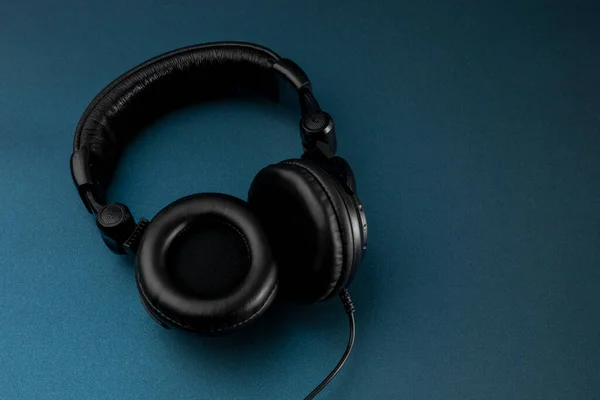 Black studio headphones with blue background and space for text — Stock Photo, Image