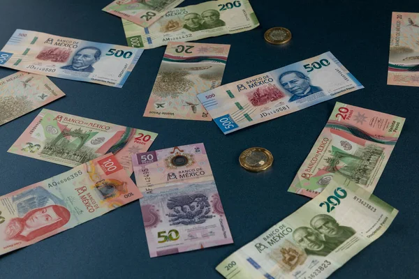 Bankovky různých nominálních hodnot mexické měny, roztroušené po modrém povrchu — Stock fotografie