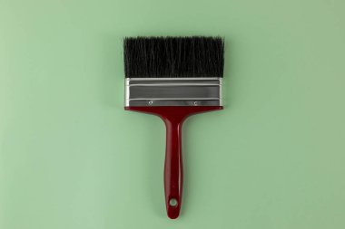 Yeşil arkaplanda, siyah kıllı kırmızı bir fırçanın üst görünümü