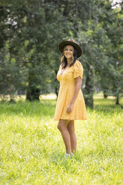 Portrait of Hispanic woman from Mexico, wearing a yellow dress and hat, with trees in the background — Foto de Stock