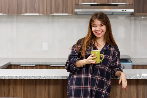 Cheerful woman at home with comfortable clothes having a cup of coffee in her kitchen — Fotografia de Stock