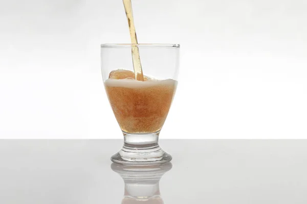 Stream of beer falling into a crystal glass is a white background — Stockfoto