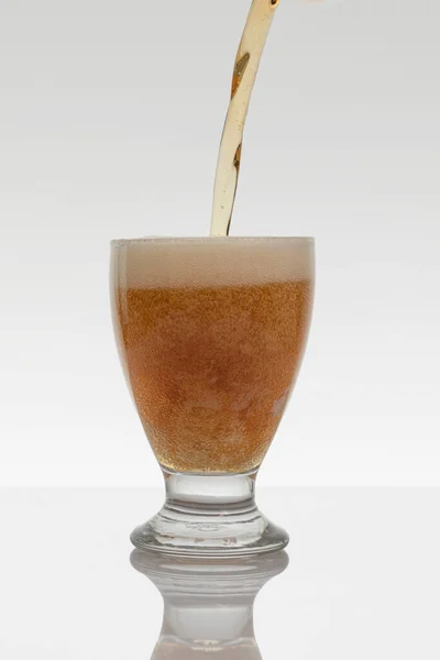 Vertical photo of a stream of beer falling into a glass on a white background — Stockfoto