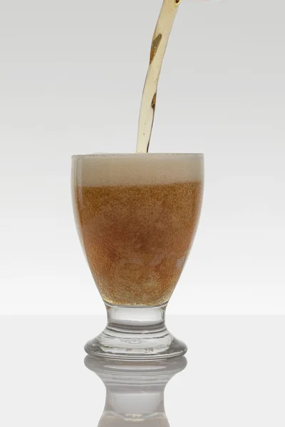 Vertical photo of a stream of beer falling into a glass on a white background Royalty Free Stock Photos