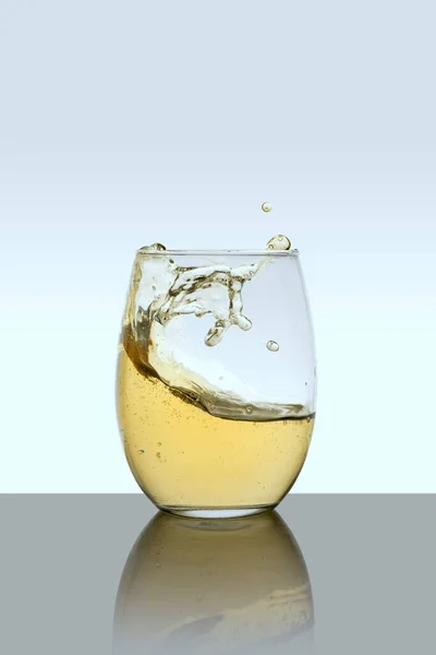 Glass cup with drink in motion with a white background — Stockfoto