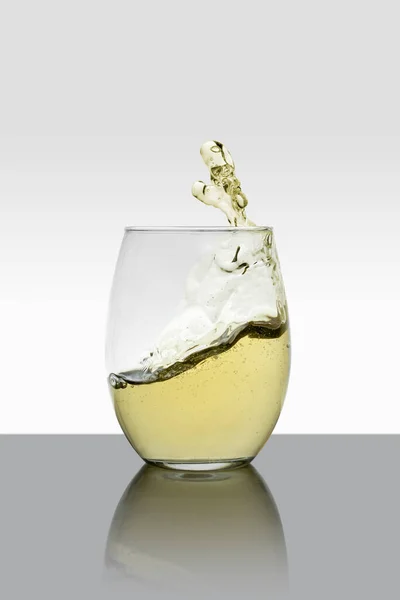 Glass cup with drink in motion with a white background — ストック写真