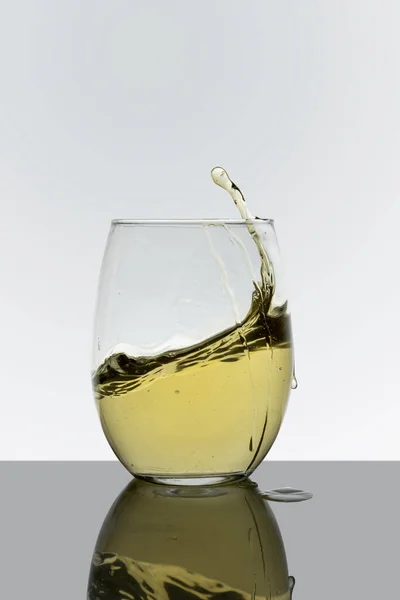 Glass cup with drink in motion with a white background — Stockfoto