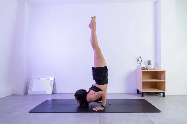 Processo posando, de uma mulher fazendo a pose escorpião em um estúdio de ioga, vestindo roupas esportivas — Fotografia de Stock