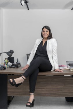 Ofis masasında oturan mutlu, kendinden emin ve başarılı Latin iş kadını. Resmi kıyafetli kadın ofisinde dinleniyor..