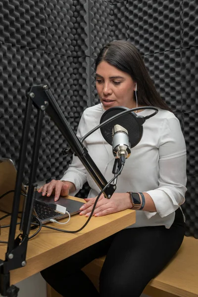Femeie vorbește într-un microfon în timp ce înregistrează un podcast, folosind o cabină audio cu izolație acustică — Fotografie, imagine de stoc