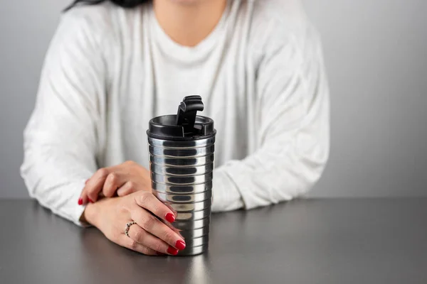 Mujer irreconocible con un termo en la mano sentada en una mesa, con espacio para copiar — Foto de Stock