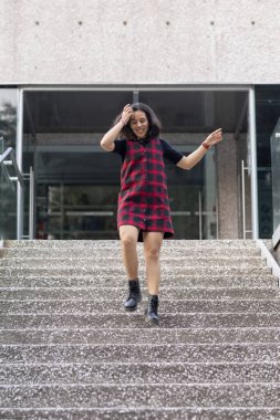 Neşeli Latin kadın hızla bir binanın merdivenlerinden aşağı iniyor.