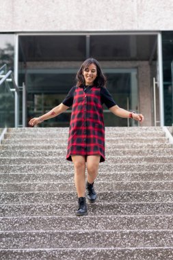 Neşeli Latin kadın hızla bir binanın merdivenlerinden aşağı iniyor.