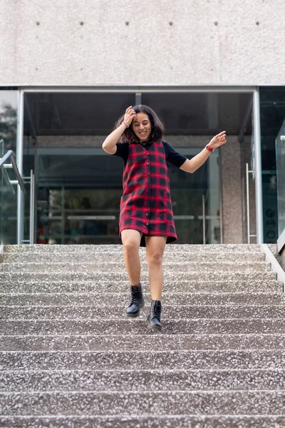 Neşeli Latin kadın hızla bir binanın merdivenlerinden aşağı iniyor.