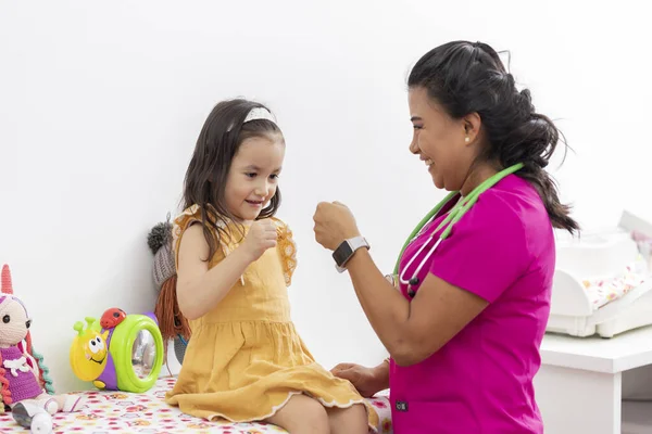 Medico pediatrico stringe la mano a una bambina che la sta visitando nel suo ufficio — Foto Stock