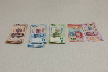 Tek başına Meksika pezosu banknotları, mezheplere göre düzenlenmiş bir masanın üzerinde..