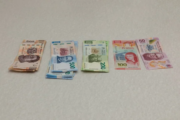 Tek başına Meksika pezosu banknotları, mezheplere göre düzenlenmiş bir masanın üzerinde..