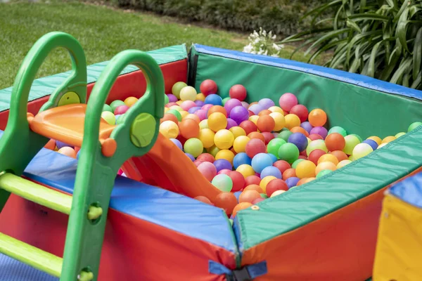 Çocukların oynaması için merdiveni olan renkli top havuzu. Bahçedeki çocuk oyunları..