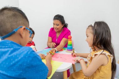 Masada oturan çocuk doktoru ve muayenehanesinde oynayan bir kaç çocuk..