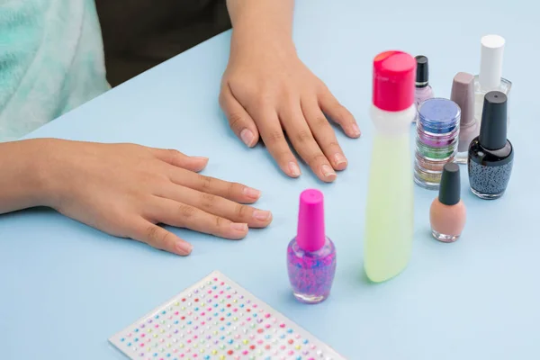 Hands of a young Latin woman, who is going to paint her nails, with varnishes and accessories.