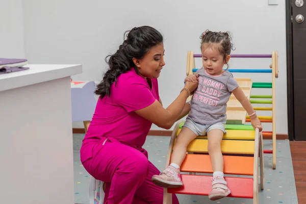 Pediatric doctor plays with a girl in the playground of her medical office.