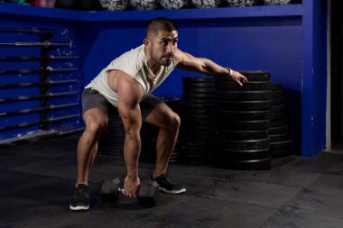 Spor kıyafetli Latin bir adam, spor salonunda halterle egzersiz yapıyor.