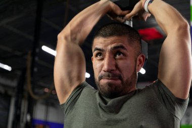 Spor salonunda dambılla triseps egzersizi yapan Latin bir sporcunun fotoğrafını çek.