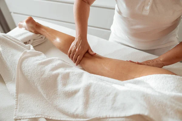Cliente femenino recibiendo masaje en la pierna en el centro de bienestar —  Fotos de Stock