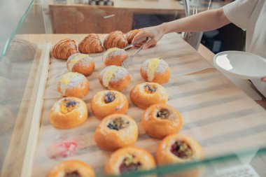 Pastanedeki vitrinden çörek alan bir kadın.