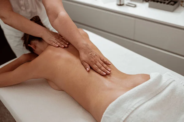 Masajista profesional que masajea a la mujer de vuelta en el salón de spa —  Fotos de Stock