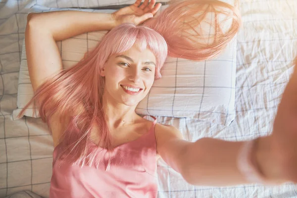 파자마를 분홍빛 머리를 긍정적 위에서 내려다보는 집에서 체크무늬 리넨이 침대에 — 스톡 사진