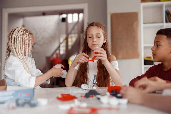 Chłopiec i dziewczęta konstruują model z detalami konstruktora w szkole — Zdjęcie stockowe