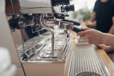 Kafede profesyonel kahve makinesi kullanan kadın barmen.