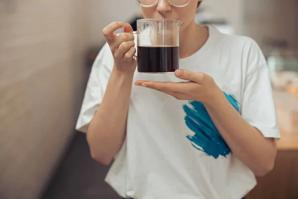 Mujer joven sosteniendo taza de vidrio de café aromático —  Fotos de Stock