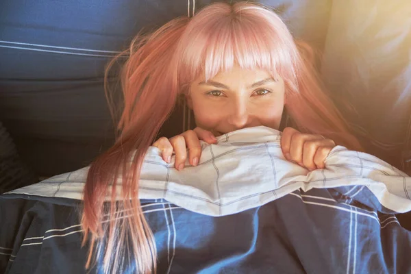Leuke vrouw met fel roze haar ligt onder zachte deken in groot bed — Stockfoto