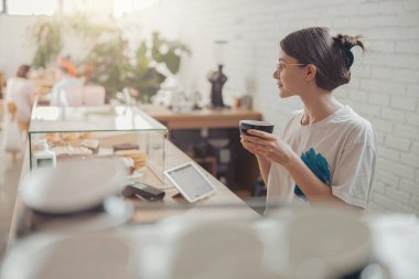 Kahve dükkanında kahve içen hoş bir genç bayan.