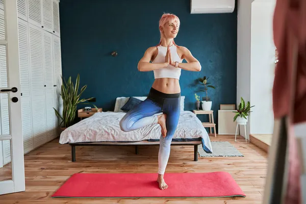 Elegante Mujer Joven Cómodo Chándal Encuentra Vrksasana Estera Cerca Cama — Foto de Stock