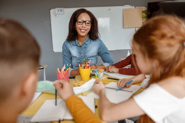 Fiatal tanár beszél a gyerekekkel az órán az osztályteremben — Stock Fotó