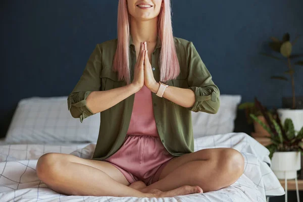 Glimlachend vrouwelijk model mediteert hand in hand in namaste mudra op groot bed closeup — Stockfoto