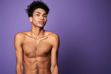 Mor arka planda Latin Amerikalı transseksüel modelin portresi. Kameraya poz veren yakışıklı genç adam.