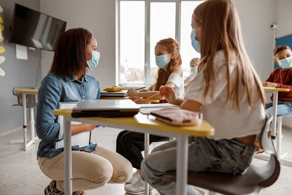 Joven maestra hablando con dos colegialas en clase — Foto de Stock