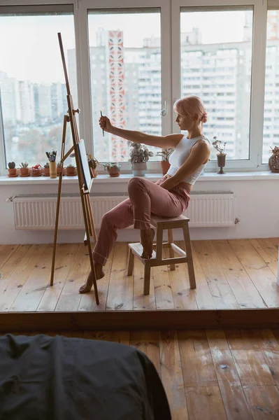전문 여성 미술가는 이젤에서 연필로 비율을 확인 한다 — 스톡 사진