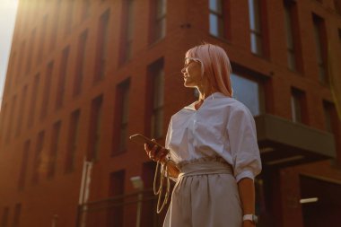 Sokakta cep telefonu olan genç bir kadın.