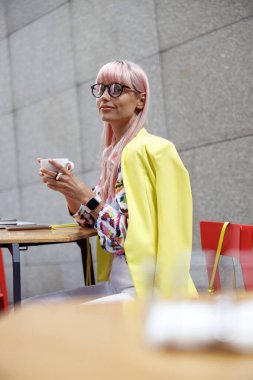 Gözlüklü, dışarıda kahve içen şık bir kadın.