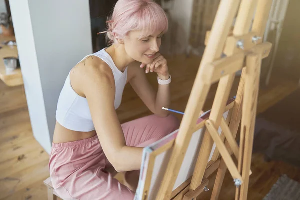 Happy artist menggambar gambar dengan pensil duduk di kayu easel — Stok Foto