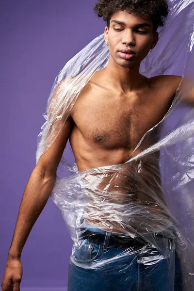 Fiatal férfi törött műanyag zacskó portréval. Érzéki transznemű férfi elpusztítani átlátszó táska kézzel — Stock Fotó
