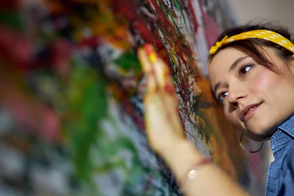 Potret wanita muda yang santai, pelukis perempuan mengoleskan cat di atas kanvas dengan jari-jari sambil menciptakan lukisan minyak abstrak modern yang besar — Stok Foto