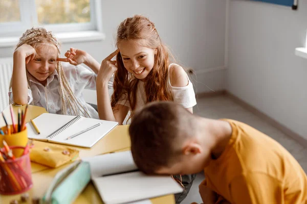 Gelukkige meisjes grappen op hun klasgenoot in de klas — Stockfoto