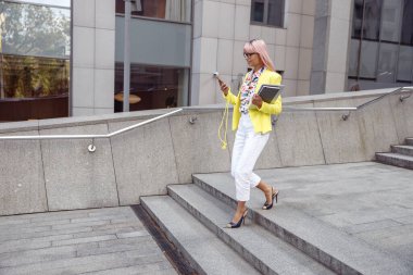 Telefonuna odaklanmış bir kadın merdivenlerden aşağı iniyor.