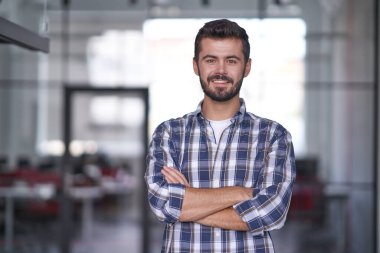 Toplantı odasında elleri katlanmış yakışıklı bir adam.